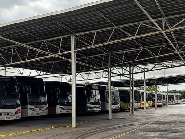 Garagem de ônibus no DF com marcas de acidente e fita de isolamento, representando tragédia em primeiro dia de trabalho.