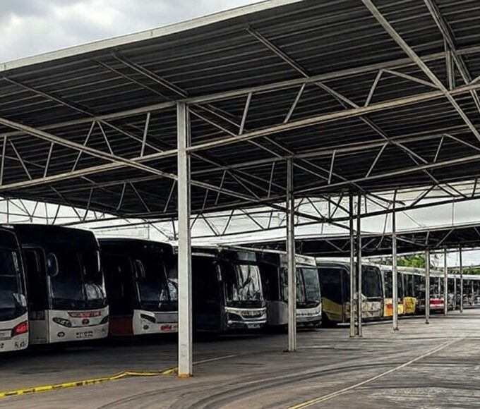 Garagem de ônibus no DF com marcas de acidente e fita de isolamento, representando tragédia em primeiro dia de trabalho.