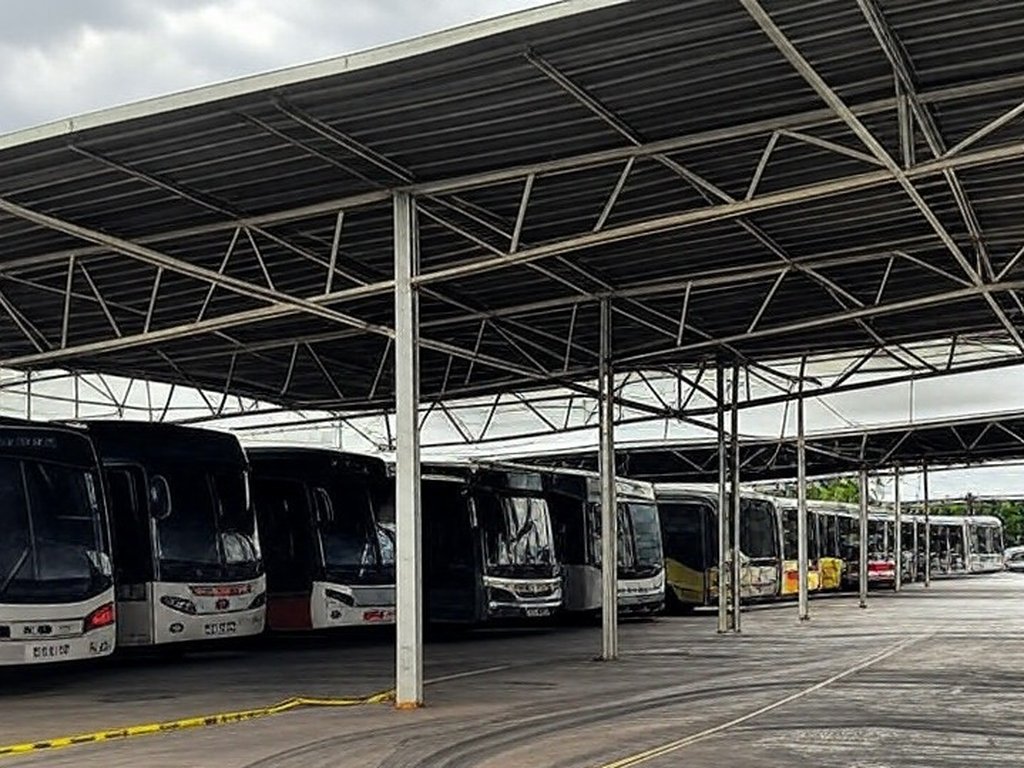 Garagem de ônibus no DF com marcas de acidente e fita de isolamento, representando tragédia em primeiro dia de trabalho.