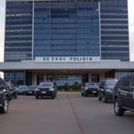 Fachada da sede da Polícia Federal em Brasília com viaturas, simbolizando investigação de ameaças a Lula e Janja em redes sociais.