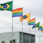 Edifício da CLDF em Brasília com bandeiras LGBTQIAPN+ em dia nublado, representando anúncio do Programa Reconhecer amid críticas.