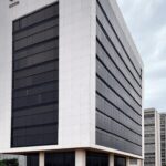 Edifício público em Brasília sob céu nublado e chuva, representando frustração no concurso da Caesb no DF.