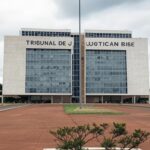 Edifício do Tribunal de Justiça em Brasília com bandeira a meio mastro, simbolizando luto pela morte de desembargador.