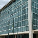 Edifício do TJDFT em Brasília com bandeiras a meio mastro, simbolizando luto pela morte de desembargador.