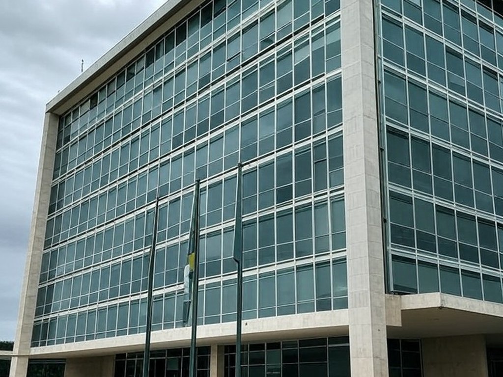 Edifício do TJDFT em Brasília com bandeiras a meio mastro, simbolizando luto pela morte de desembargador.