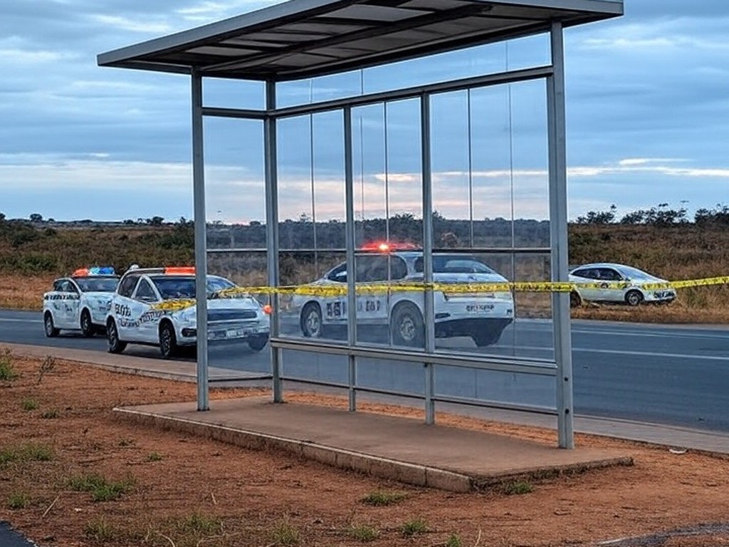 Parada de ônibus na DF-150 com fita de isolamento policial e viaturas da PMDF, cena de investigação em rodovia no Distrito Federal.