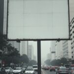 Rua em São Paulo com outdoor vazio representando polêmica efêmera da campanha pé direito e fragilidade da atenção pública.