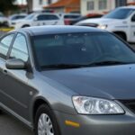 Carro com marcas de bala em rua de São Sebastião, cercado por fita de isolamento e viaturas da polícia, investigando acerto de contas.