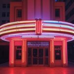 Fachada iluminada de cinema em São Paulo representando sucesso de bilheteria de atrizes como Zoe Saldaña e Scarlett Johansson.