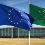 Bandeiras da UE e Mercosul em frente ao Palácio do Itamaraty em Brasília, representando acordo de livre-comércio histórico.