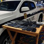 Viatura da polícia no Carnaval de Brasília com celulares furtados recuperados, cena noturna festiva sem pessoas.