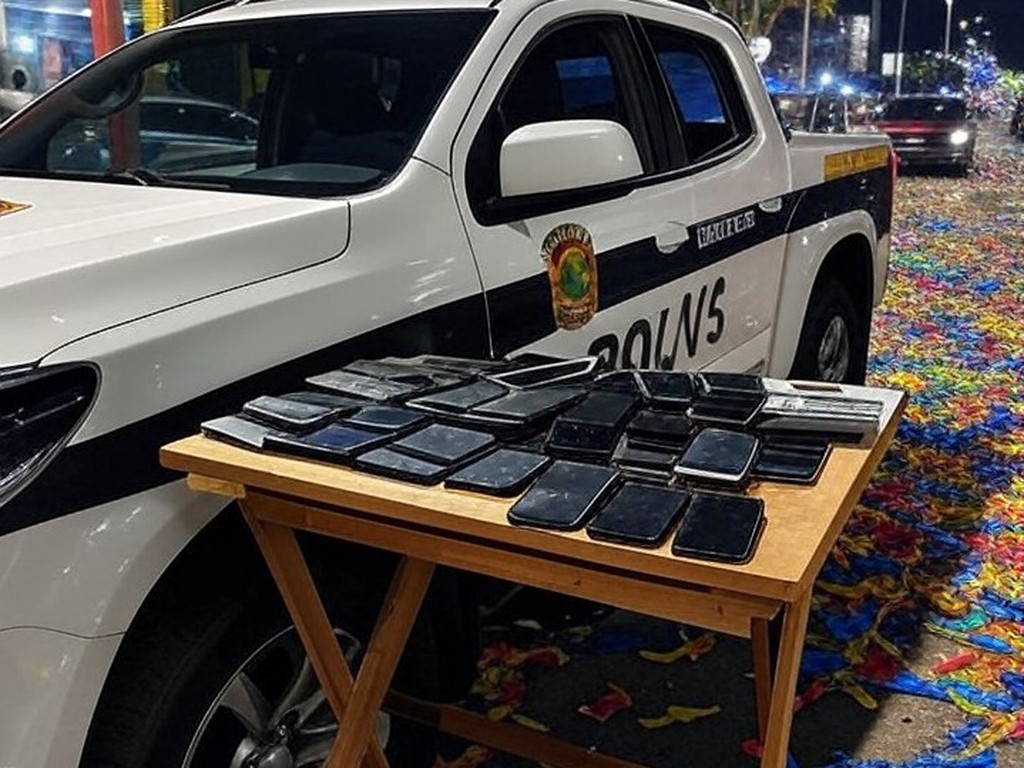 Viatura da polícia no Carnaval de Brasília com celulares furtados recuperados, cena noturna festiva sem pessoas.