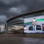 Fachada da CLDF em Brasília com símbolos de lentidão legislativa e falhas em transmissão ao vivo.