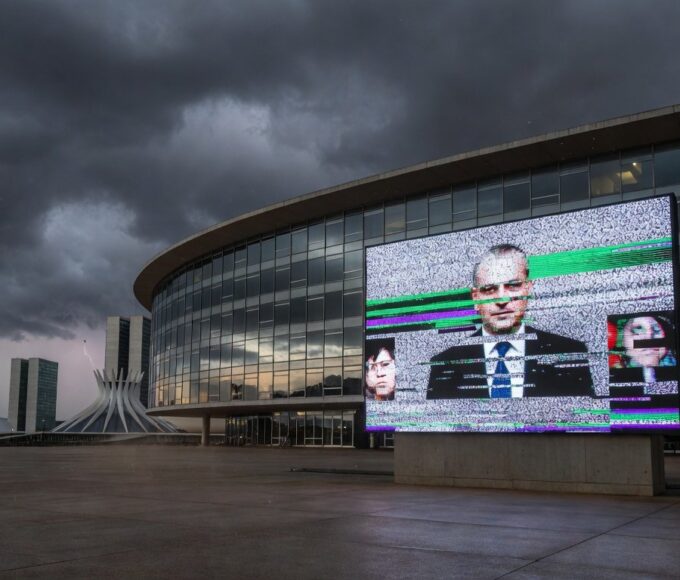 Fachada da CLDF em Brasília com símbolos de lentidão legislativa e falhas em transmissão ao vivo.