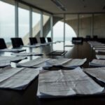 Sala de reuniões vazia na CLDF em Brasília, com documentos e atmosfera de suspeitas e falta de transparência em encontro com presidente do BRB.