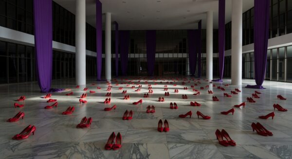 Edifício da CLDF em Brasília com fitas roxas simbolizando luta contra violência a mulheres, em tom negativo.