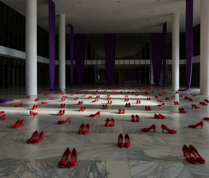 Edifício da CLDF em Brasília com fitas roxas simbolizando luta contra violência a mulheres, em tom negativo.