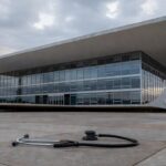 Edifício da CLDF em Brasília com símbolos de saúde e segurança deteriorados, representando falhas em avanços no DF.