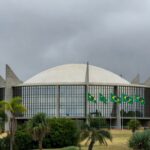 Fachada da Câmara Legislativa do DF em Brasília, com céu nublado, representando críticas à Procuradoria da Mulher.