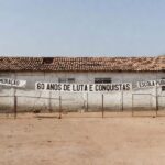 Escola pública em Sobradinho com fachada deteriorada e banners de 60 anos, destacando deficiências educacionais.