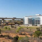 Hospital moderno e viadutos em São Sebastião, DF, representando investimentos em infraestrutura.