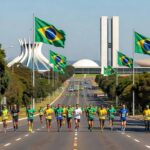 Maratona em Brasília celebrando 66 anos da cidade, com arquitetura icônica como Congresso Nacional ao fundo.