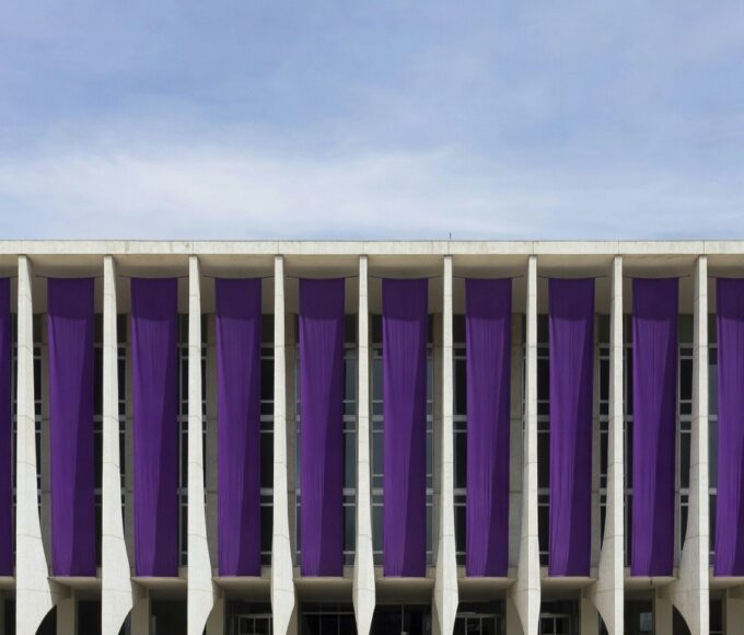 Edifício governamental em Brasília com faixas roxas representando programas contra violência doméstica da Sejus-DF.