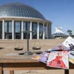 Fachada do CNJ em Brasília com balança da justiça e revistas de moda, simbolizando combate a violações trabalhistas no DF.
