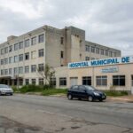 Hospital público no Brasil com estrada ao lado, representando caronas diárias para apoiar familiar em coma após cirurgia.
