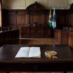 Sala legislativa com documento de título honorário e bandeiras brasileiras