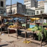 Feira livre brasileira com barracas vazias, crítica a licitações sem inclusão social